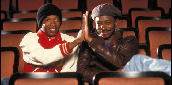 Two men giving each other a high five in a movie theater, from the movie Hollywood Shuffle
