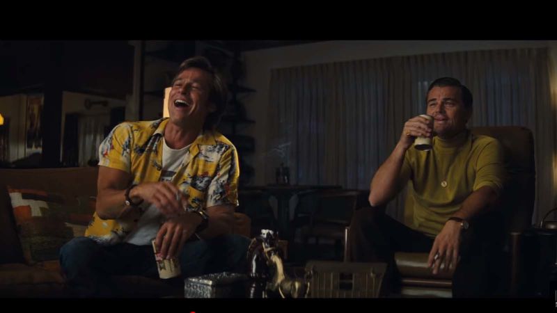 two men laughing while watching a movie